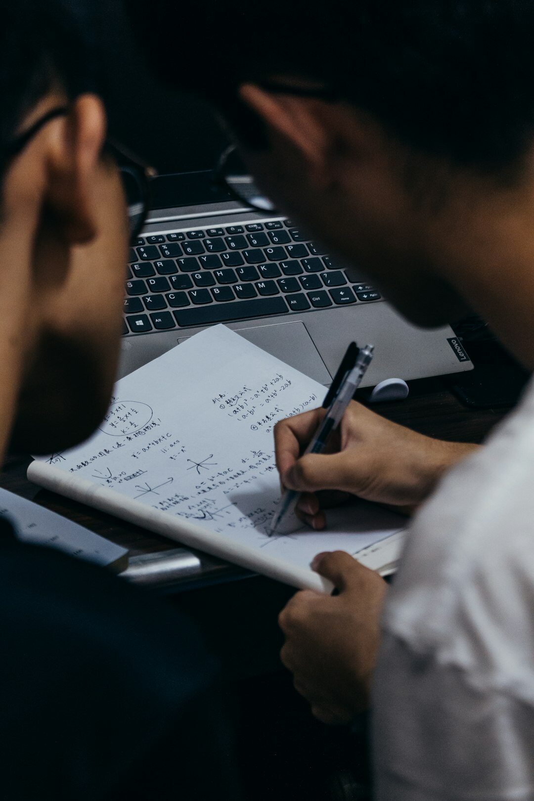 Two engineers collaborating over a laptop writing a project report